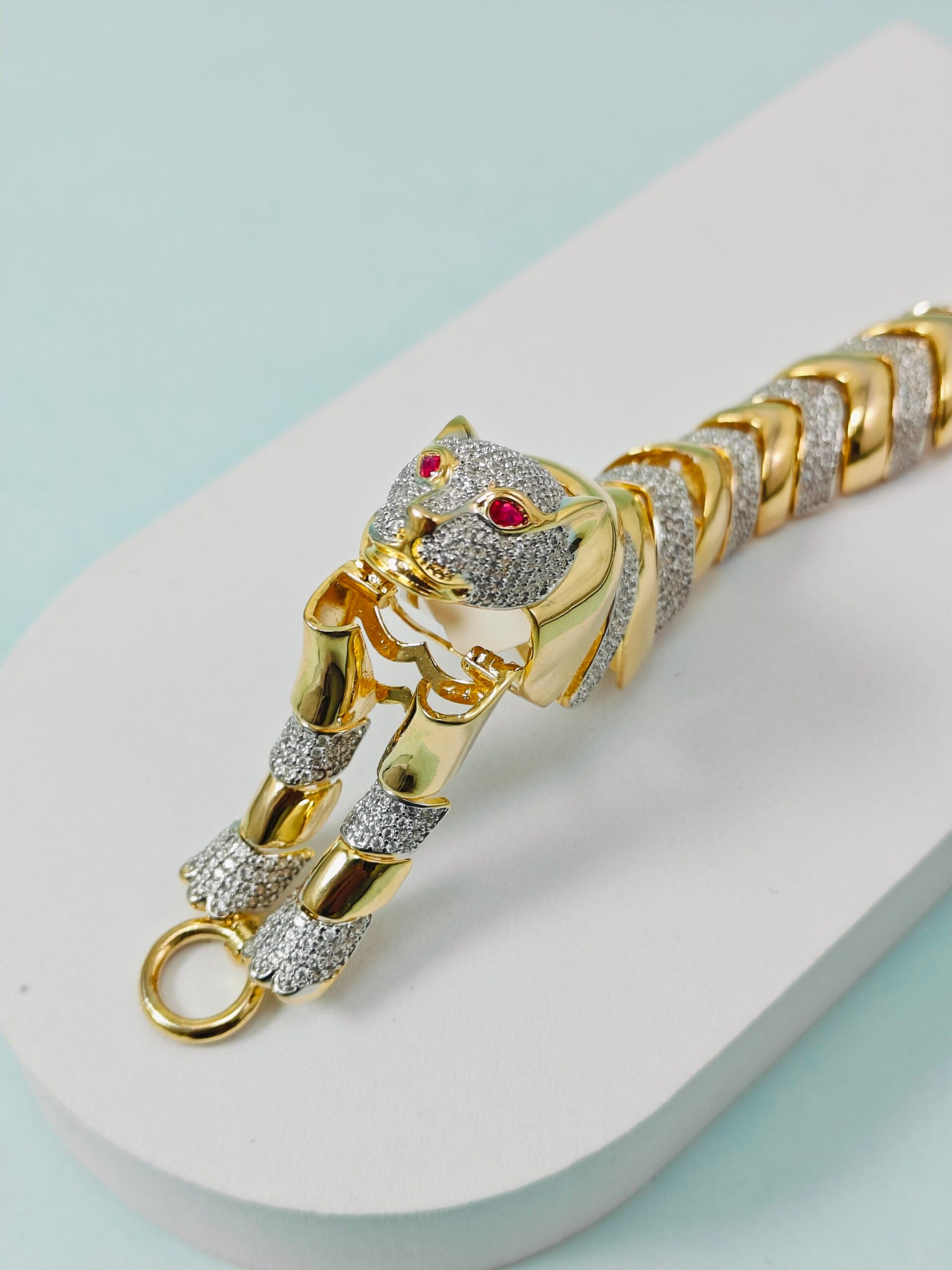 Gold panther bracelet with gemstones on a light blue background